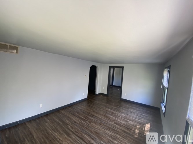 A room with wooden flooring and white walls.