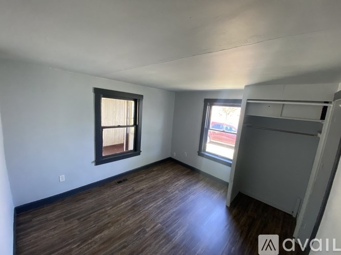 A room with wooden flooring and two windows.