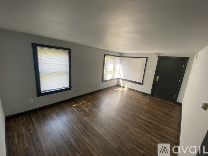 A room with wooden flooring and a window with blinds.
