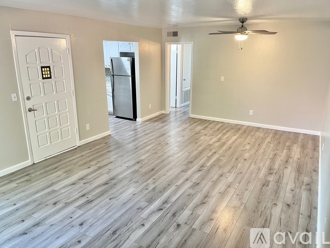 A spacious room with wooden flooring and a ceiling fan.