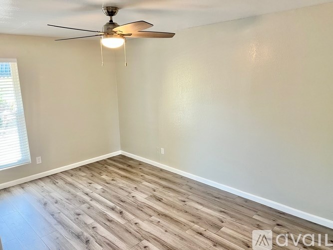 A room with a ceiling fan and wooden flooring.