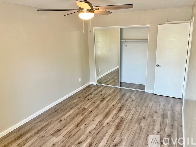 A room with a ceiling fan and wooden flooring.
