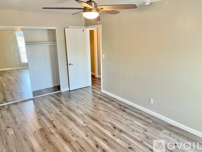 A room with a ceiling fan and wooden flooring.