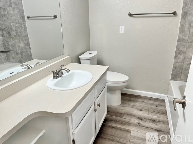 A bathroom with a sink, toilet, and a mirror.