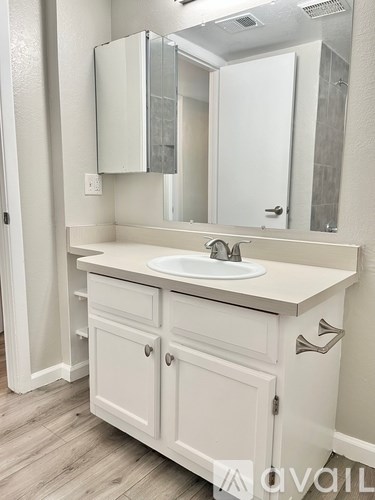 A white bathroom vanity with a sink and mirror.