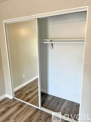 A white closet with a mirrored door and a shelf.