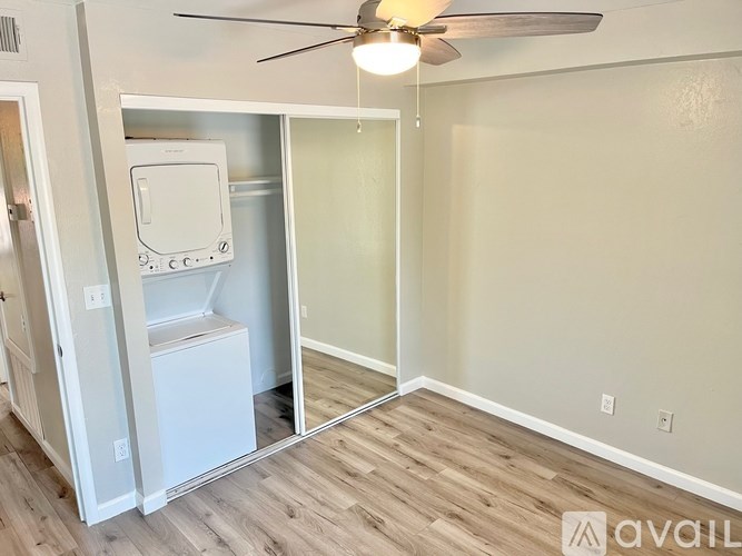 A room with a white fridge and a ceiling fan.