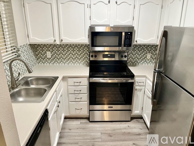 A kitchen with white cabinets and a checkered backsplash.