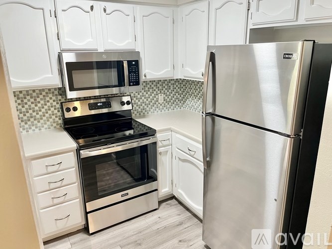 A kitchen with a stainless steel refrigerator and a stove with an oven.