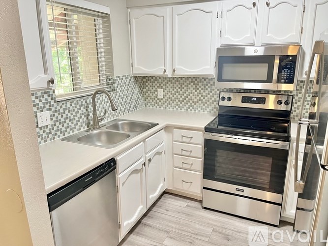 A kitchen with white cabinets and a black and white checkered backsplash.
