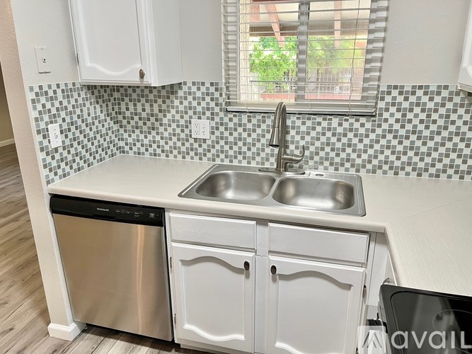 A kitchen with a checkered backsplash and a window.