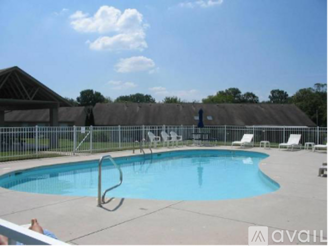 A pool with a diving board and chairs around it.