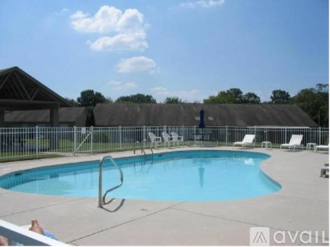 A pool with a diving board and chairs around it.