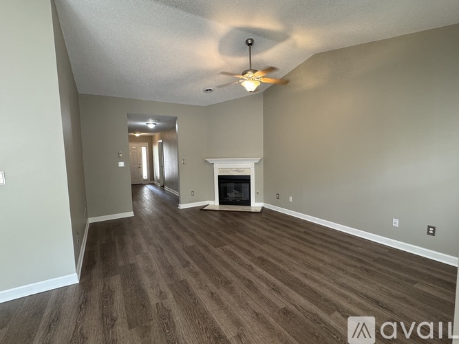 A spacious living room with wood flooring and a fireplace.