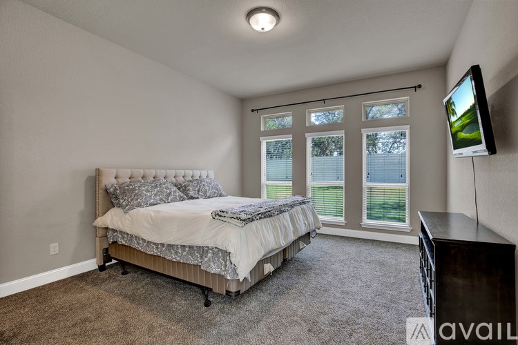 A bedroom with a bed, a television, and a window with blinds.