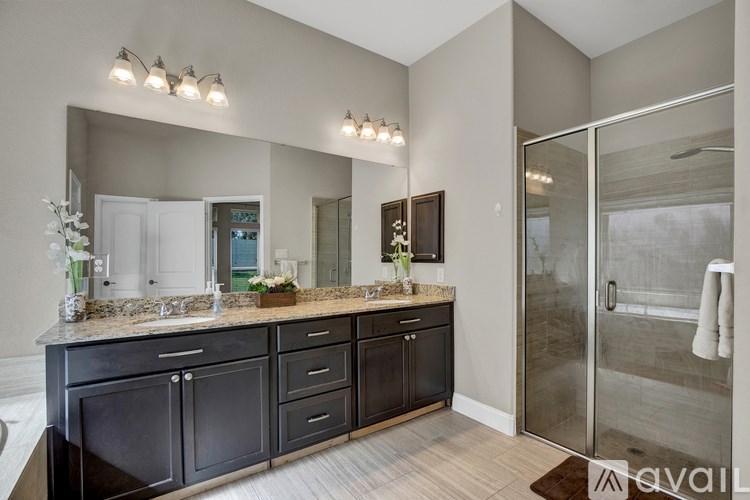 A bathroom with a vanity, mirror, and shower.