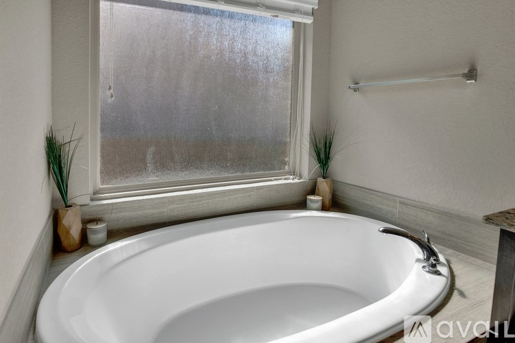 A white bathtub is in a bathroom with a window above it.