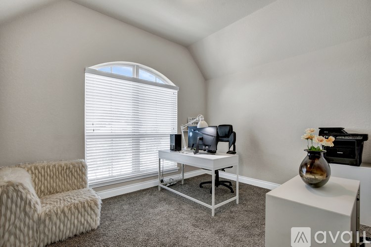 A room with a couch, a desk with a computer, and a printer on a shelf.