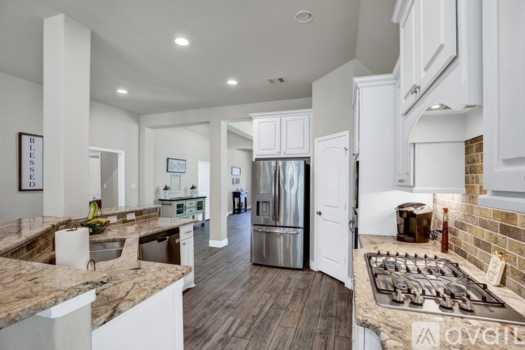 A modern kitchen with white cabinets and a wooden floor.