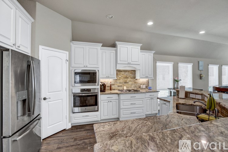 A kitchen with white cabinets and a brick backsplash.