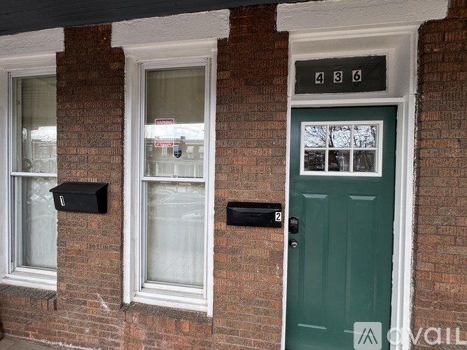 A house with a green door and mailboxes on the wall.
