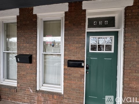 A house with a green door and mailboxes on the wall.