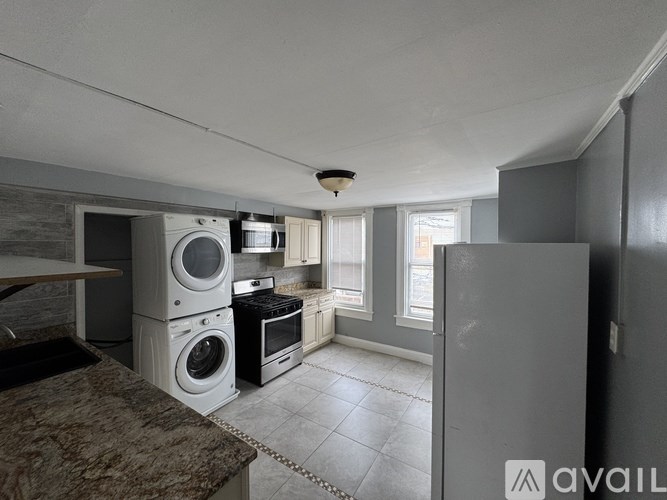 A kitchen with a washing machine and dryer stacked on top of each other.