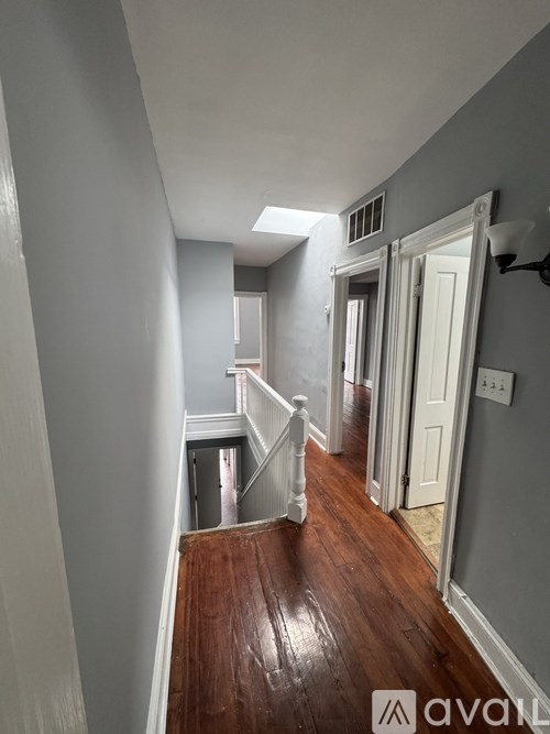 A hallway with a wooden floor and white walls.