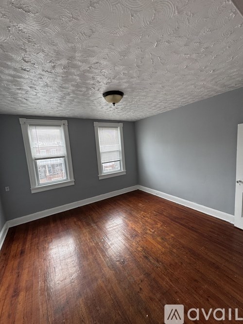 A room with wooden floors and a textured ceiling.