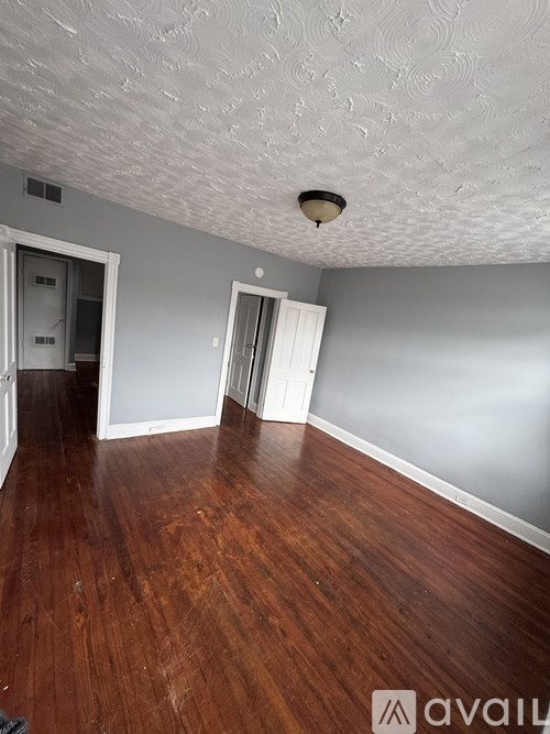 A room with wooden floors and a textured ceiling.