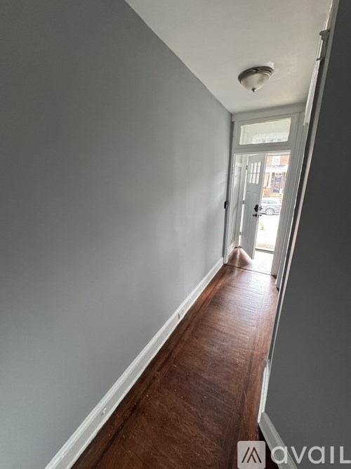 A hallway with a wooden floor and white walls.