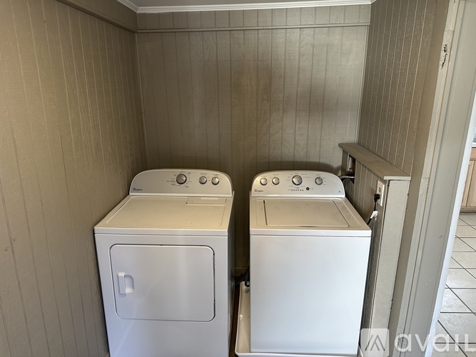 Two white front loading washing machines in a small laundry room.