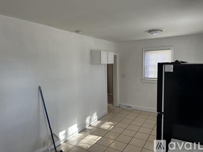 A room with white walls and a black refrigerator.