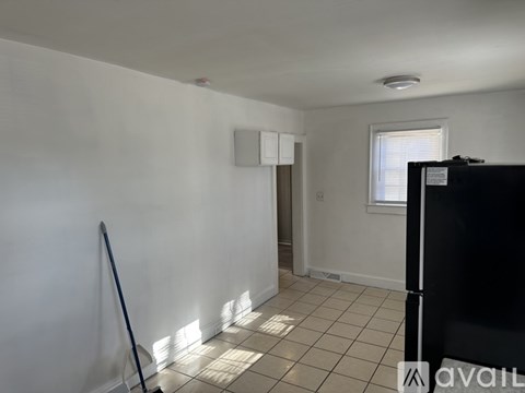 A room with white walls and a black refrigerator.