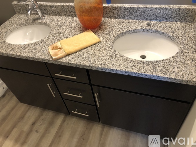 A bathroom counter with two sinks and a bottle of orange liquid.