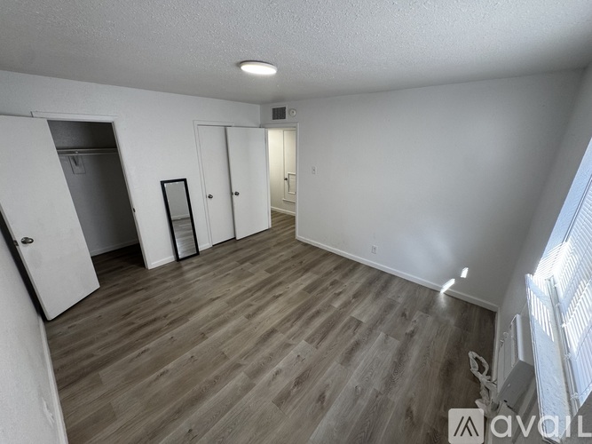 A spacious room with wooden flooring and white walls.
