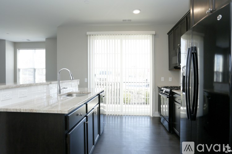 A modern kitchen with black appliances and a marble countertop.
