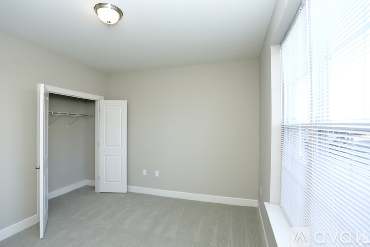 A room with a white door and a window with blinds.