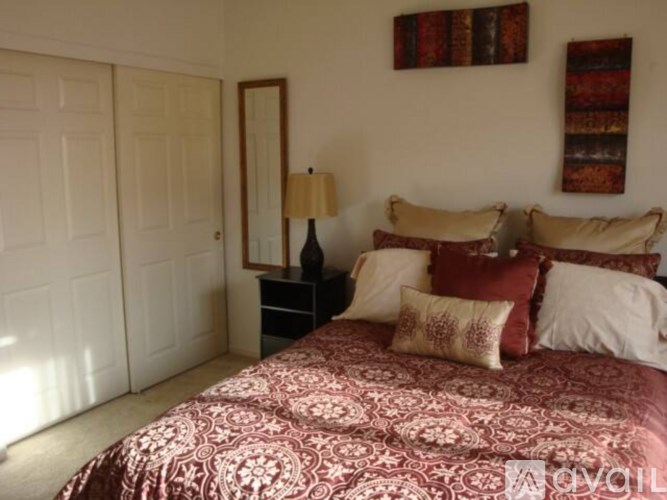 A bedroom with a bed, nightstand, and a mirror.