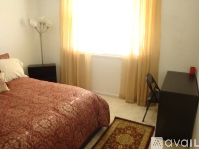 A bedroom with a red bedspread and a red rug.