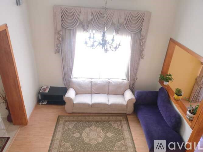 A living room with a white sofa and a chandelier.
