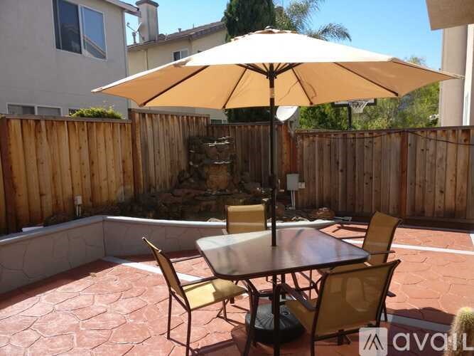 A patio with a table and chairs and an umbrella.