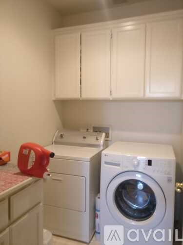 A red bottle is on top of a white washing machine.