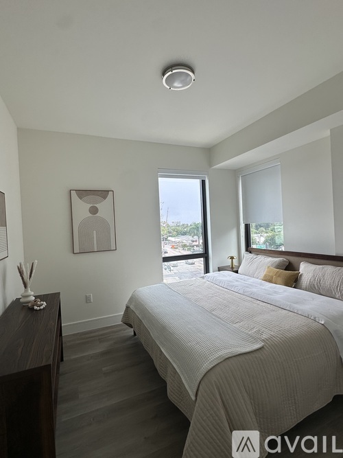 A bedroom with a large bed and a window overlooking the city.