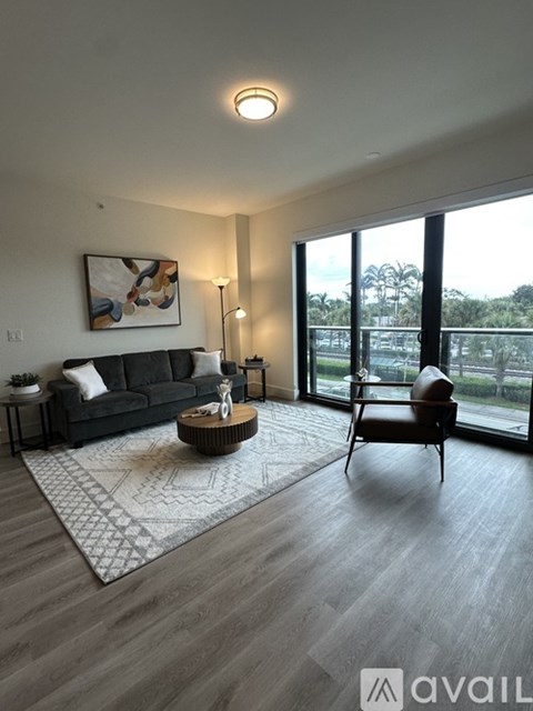 A living room with a black couch, a coffee table, and a painting on the wall.