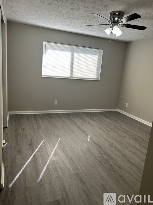 A room with a ceiling fan and a window with blinds.