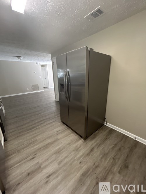 A kitchen with a stainless steel refrigerator and wooden flooring.
