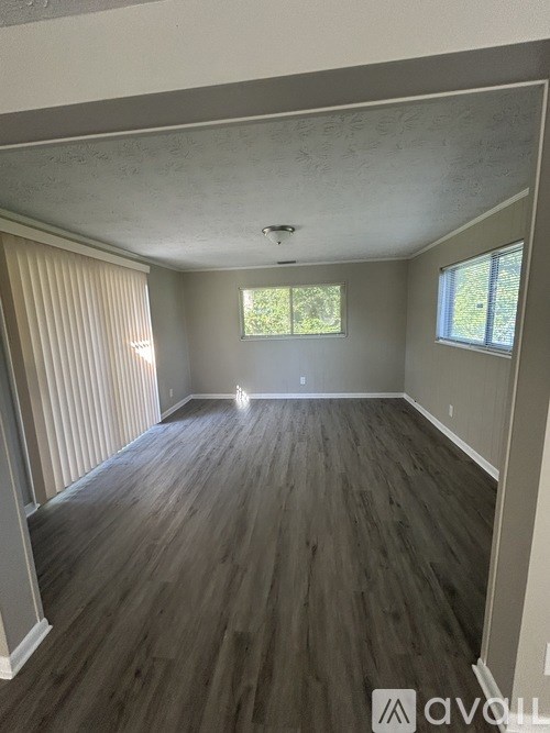 A room with wooden flooring and a window with blinds.