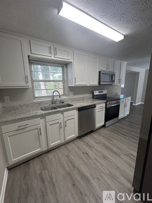 A kitchen with white cabinets and a wooden floor.