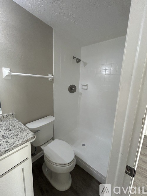 A white toilet in a small bathroom with a shower.
